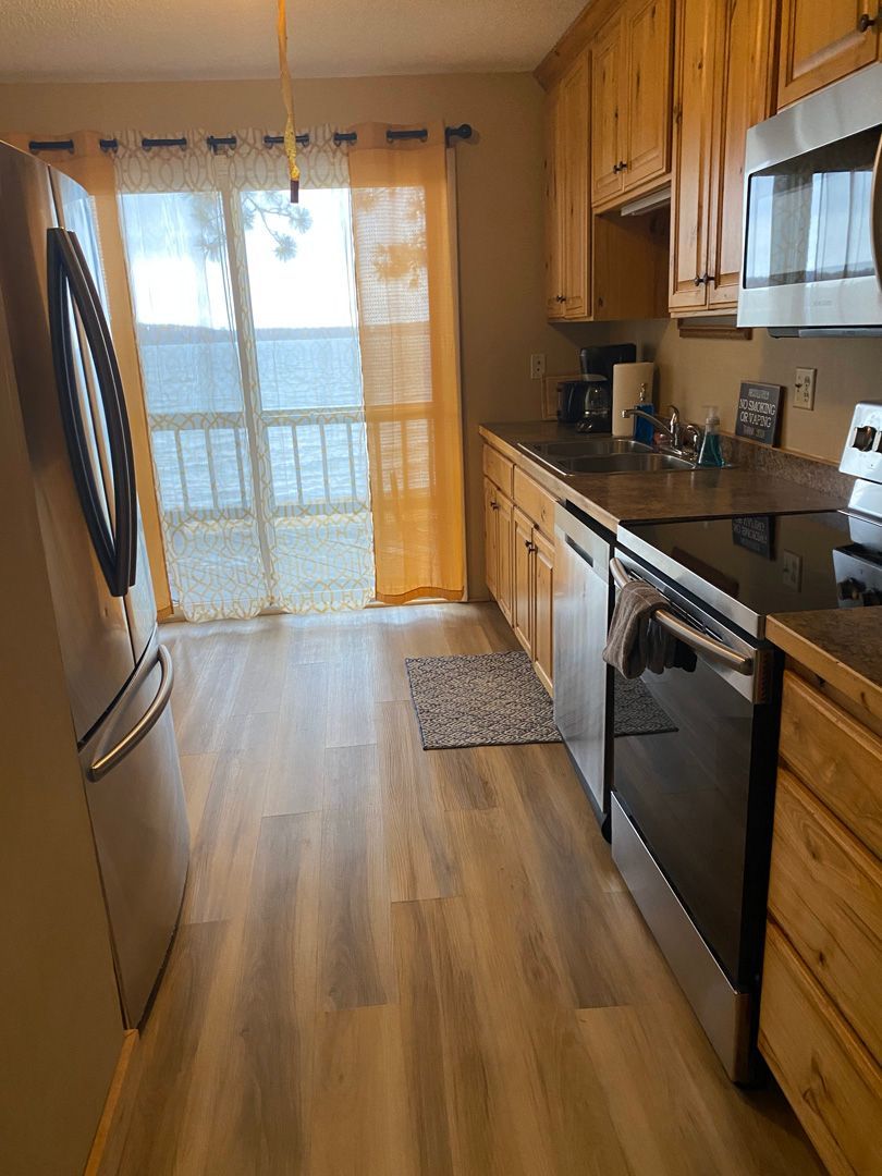 A kitchen with wooden cabinets , stainless steel appliances , a refrigerator and a stove.