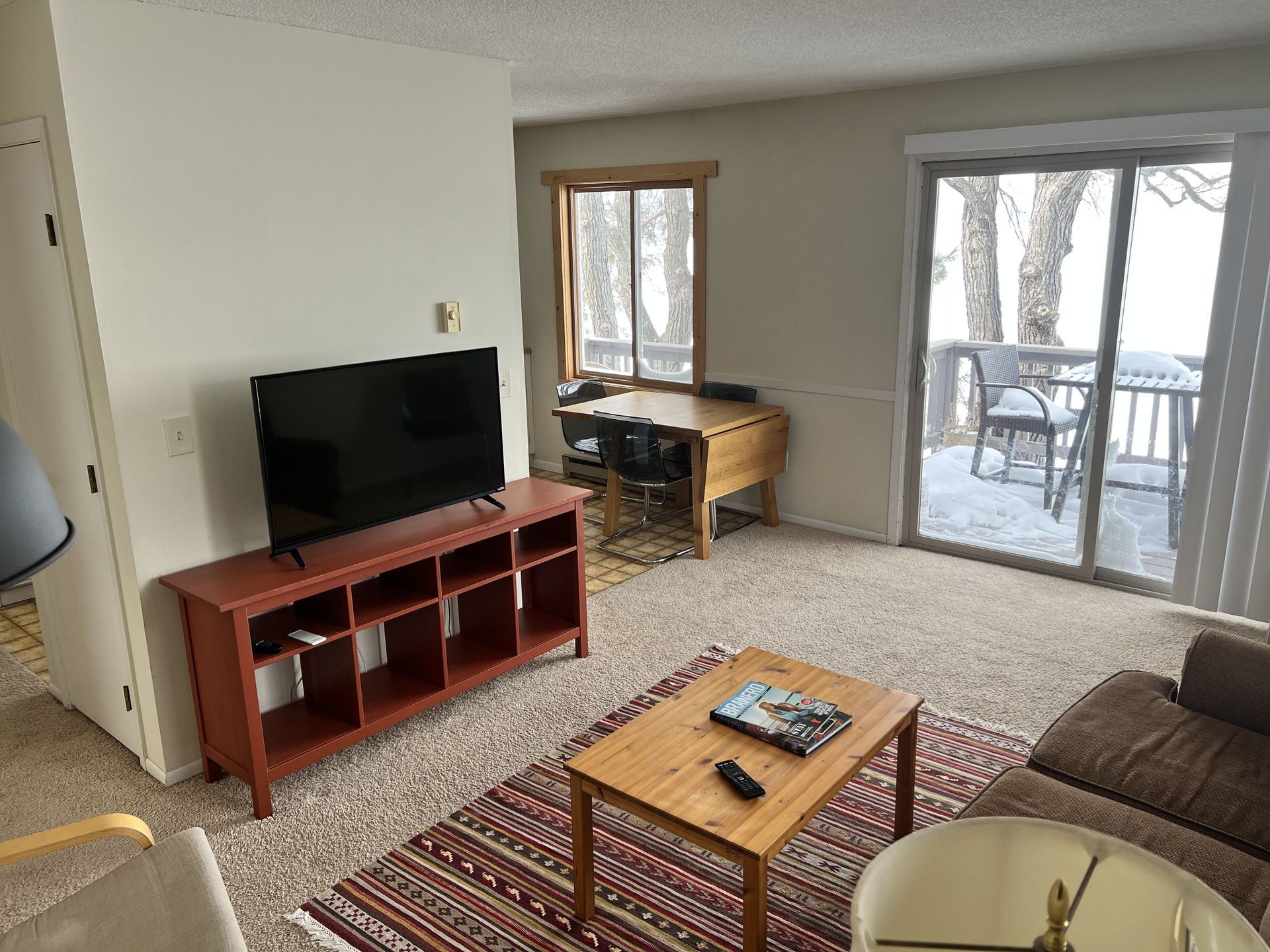 A living room with a couch , table , television and sliding glass doors.