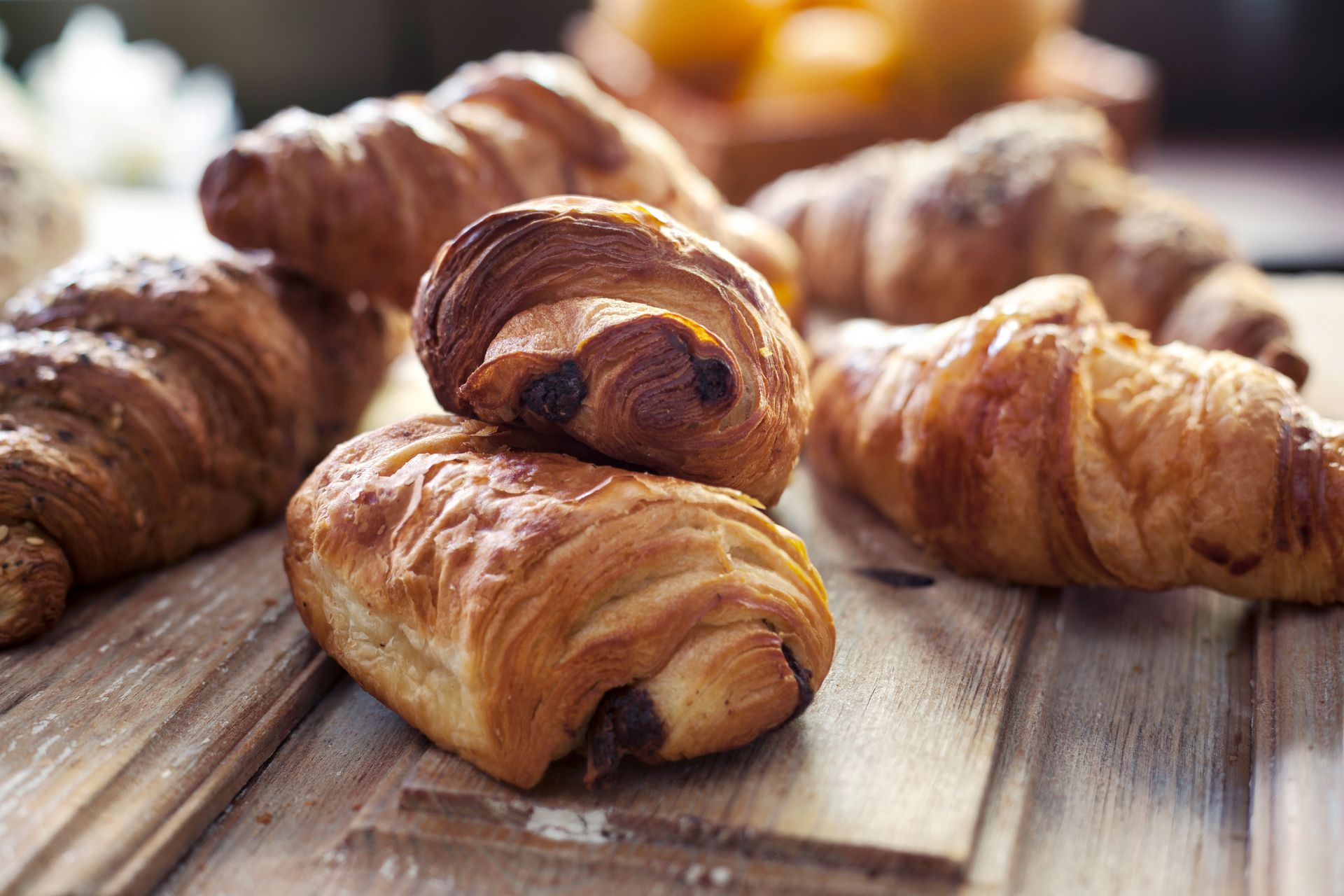 Gros plan sur un assortiment de croissants et de pains au chocolat dorés disposés sur une surface en bois.