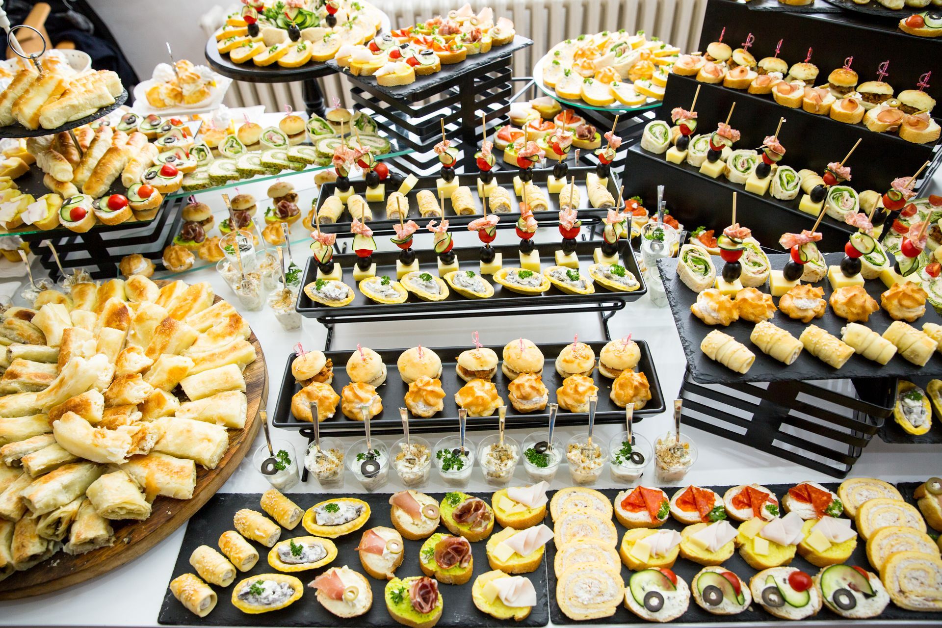 Table de traiteur avec un large choix d'amuse-gueules : sandwichs, canapés, mini-burgers et brochettes.