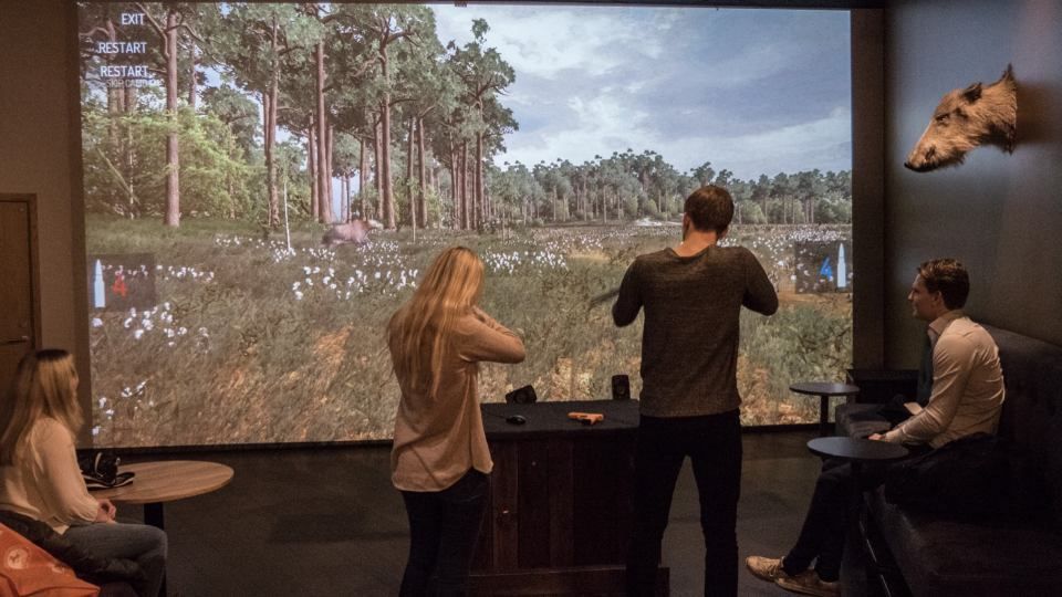 Kaksi henkilöä pelaa viihdeammuntasimulaattorilla