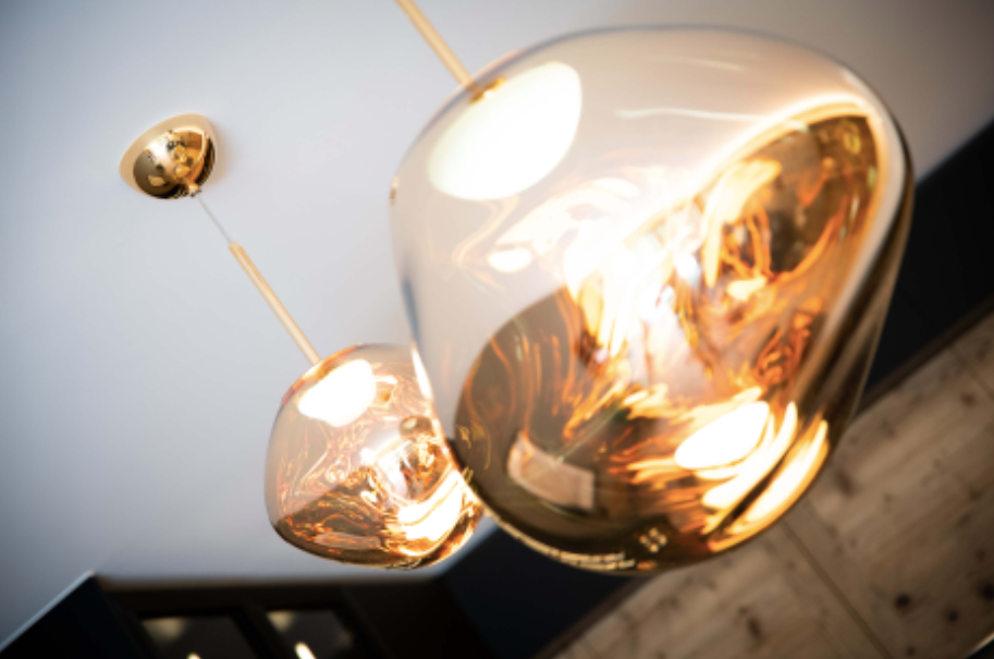 Salon chaleureux avec lambris, chaises beiges, banquette en cuir de vache, table à manger et un bol décoratif orange sur une grande table.