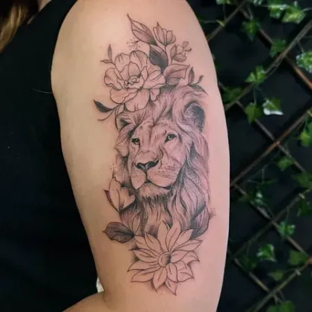 Una mujer tiene un tatuaje de un león y flores en su brazo.