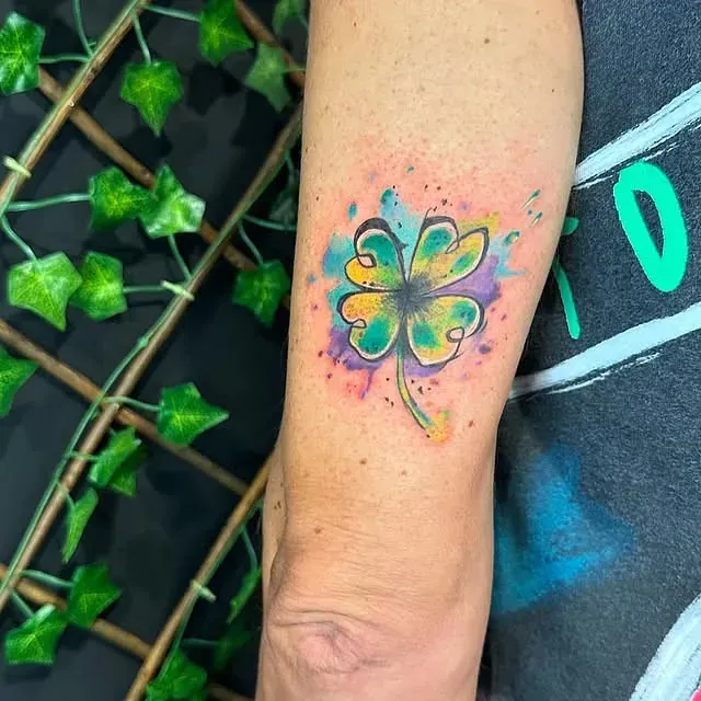 Una persona tiene un tatuaje de un trébol de cuatro hojas en el brazo.