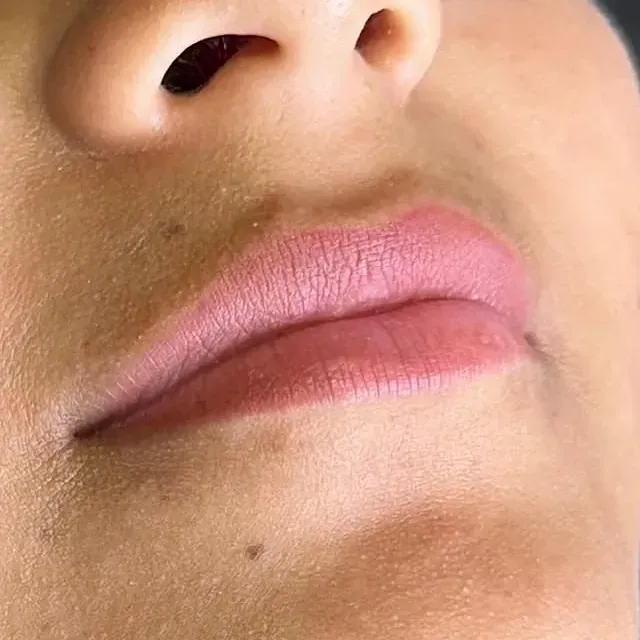 Un primer plano de los labios de una mujer con lápiz labial rosa.