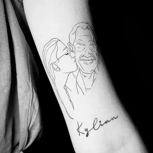 Un tatuaje de una mujer besando a un hombre en el antebrazo.