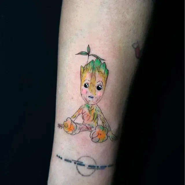 Un tatuaje de un bebé Groot en el brazo de una persona.