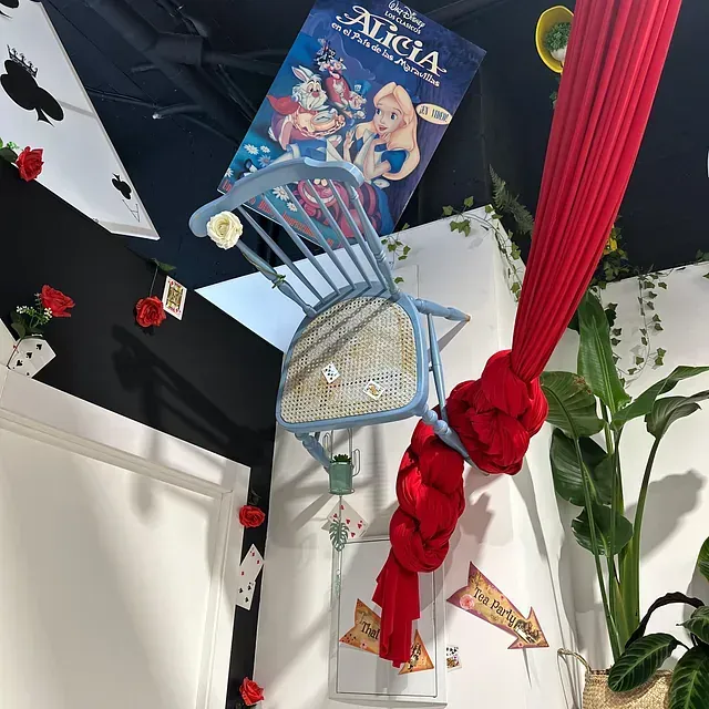 Una silla colgando del techo con un libro titulado Alicia encima.