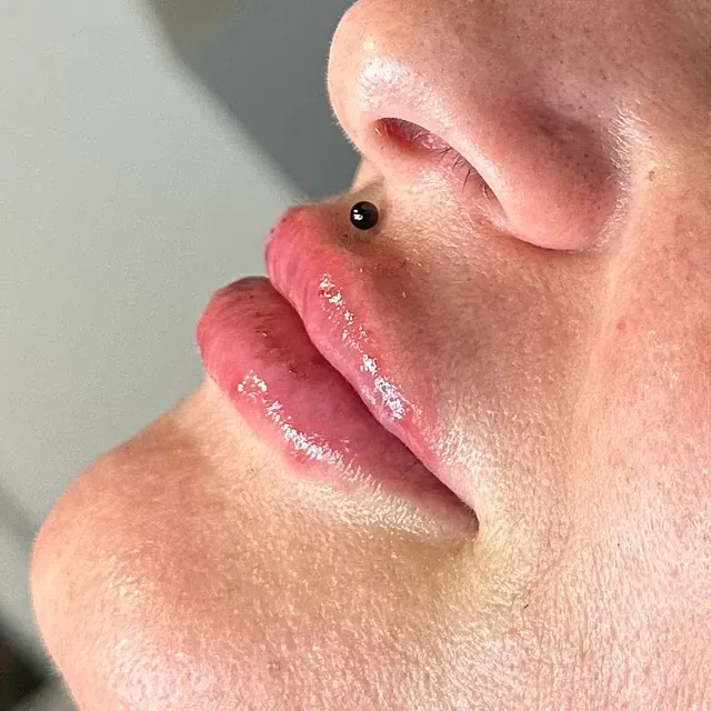 Un primer plano de los labios de una mujer con un anillo en la nariz.