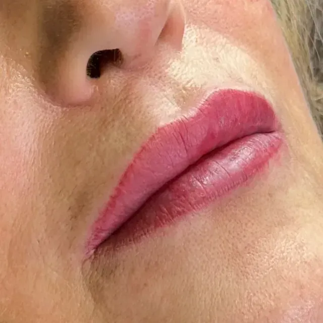 Un primer plano de los labios de una mujer con lápiz labial rosa.