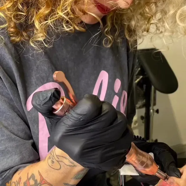 Una mujer con cabello rizado se está haciendo un tatuaje en el brazo.