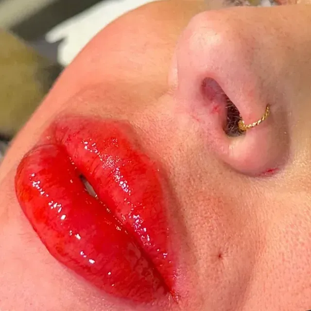 Un primer plano de los labios rojos de una mujer con un anillo en la nariz.