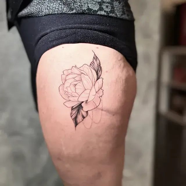 Una mujer tiene un tatuaje de una rosa en el muslo.