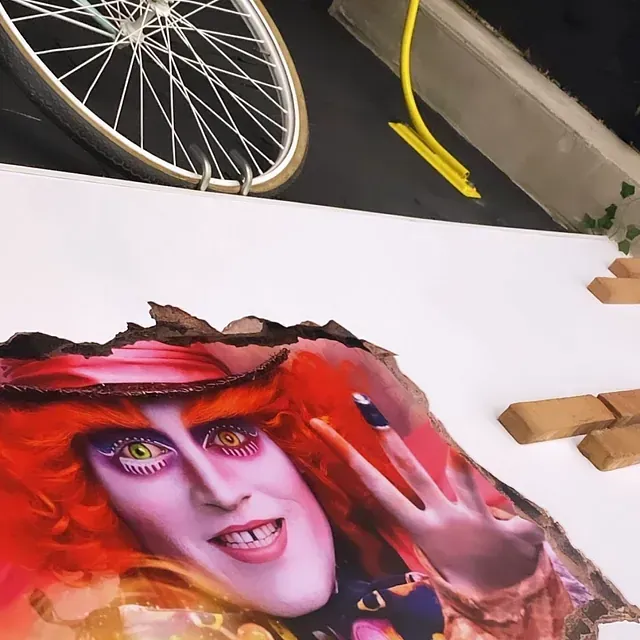 Una pintura de Alicia en el país de las maravillas con una rueda de bicicleta al fondo.