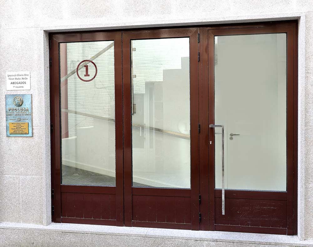 Puerta de cristal marrón con el número 1 que da a una escalera. Hay un cartel a la izquierda.