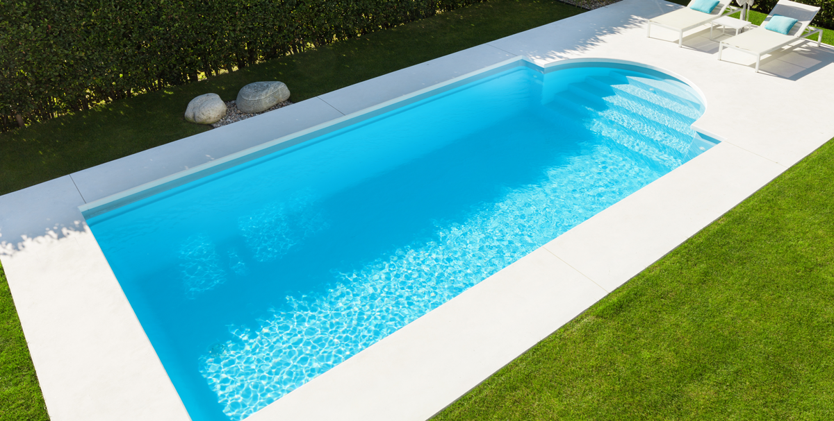 Piscine dans un jardin entourée de pelouse