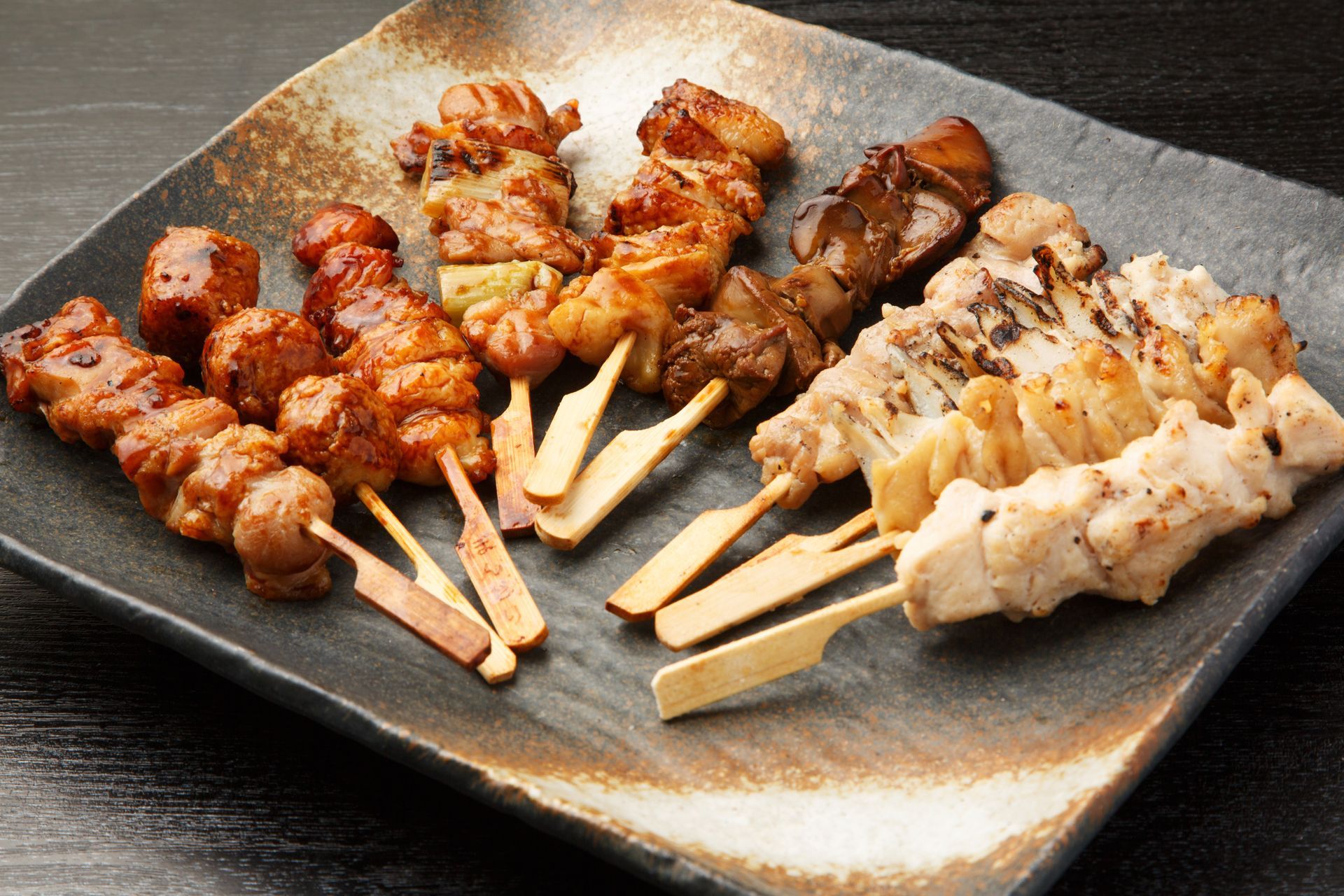 Steak saisi et tranché, servi sur un plateau en bois, garni de graines de sésame, de piments jalapeños et d'oignon rouge.