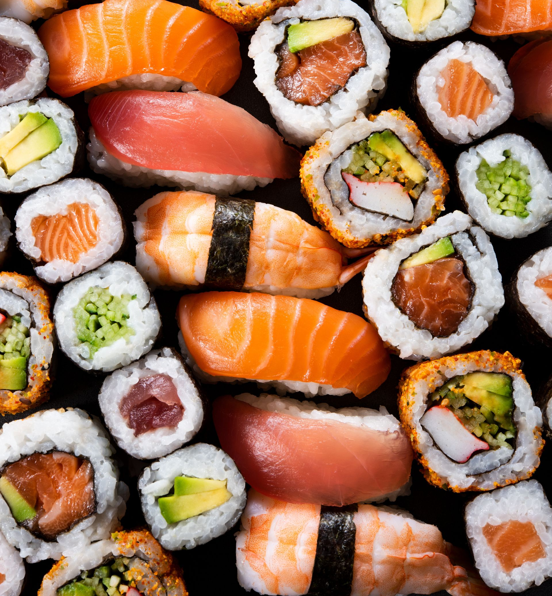 Assortiment de rouleaux de sushi et de nigiris au saumon, au thon, à l'avocat et au riz.