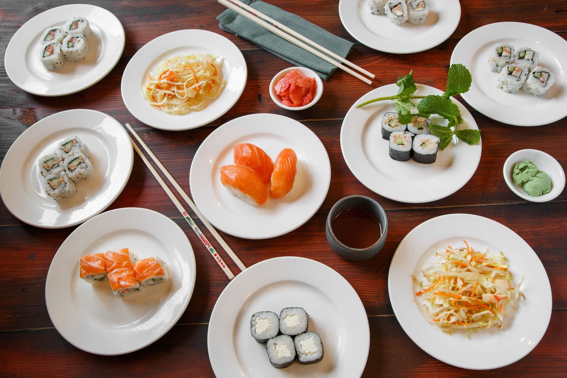 Sushis et accompagnements disposés sur des assiettes blanches, sur une table en bois.