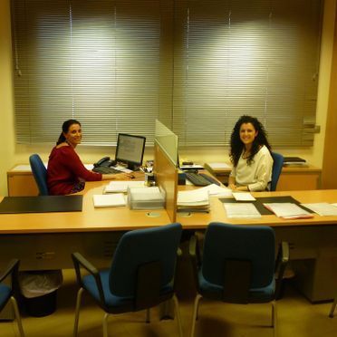 Dos mujeres están sentadas en escritorios en una oficina.