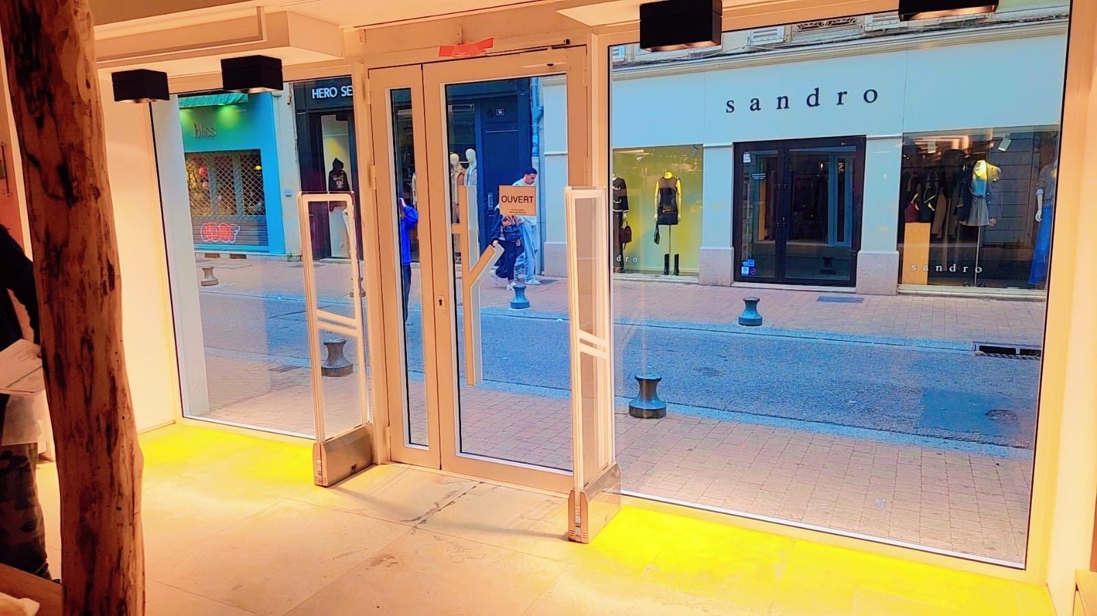 Vue sur une rue commerçante depuis l'intérieur d'un magasin.