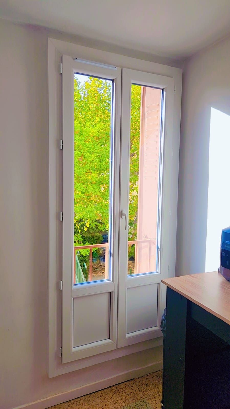 Porte-fenêtre de petit balcon donnant sur un jardin.