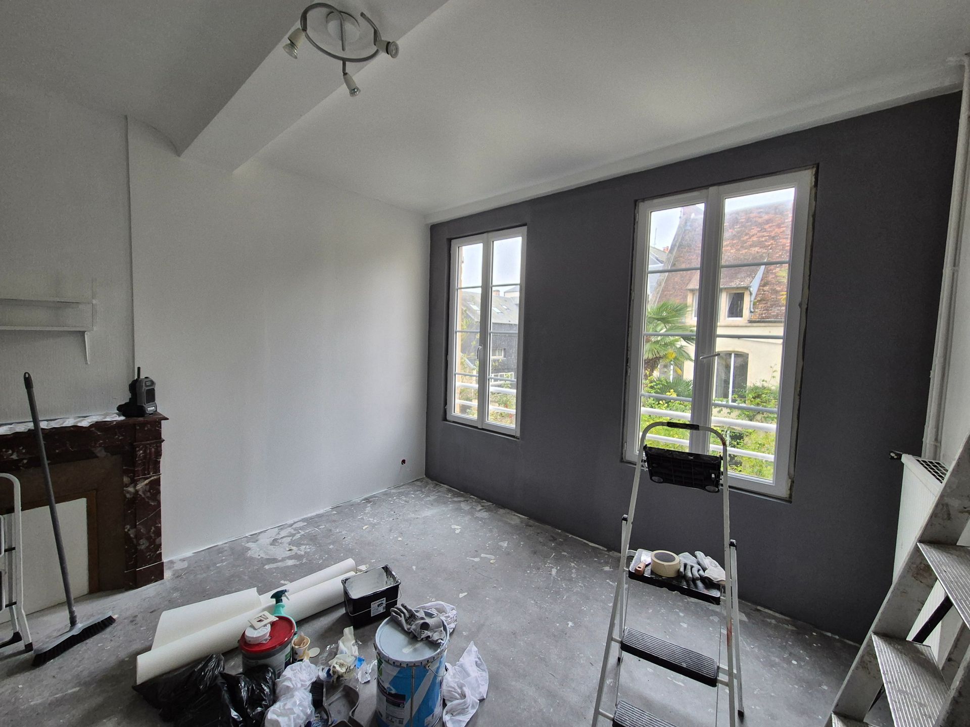 Travaux de peinture terminés dans une pièce avec un échafaudage, les murs peints en blanc et en gris anthracite – partie après