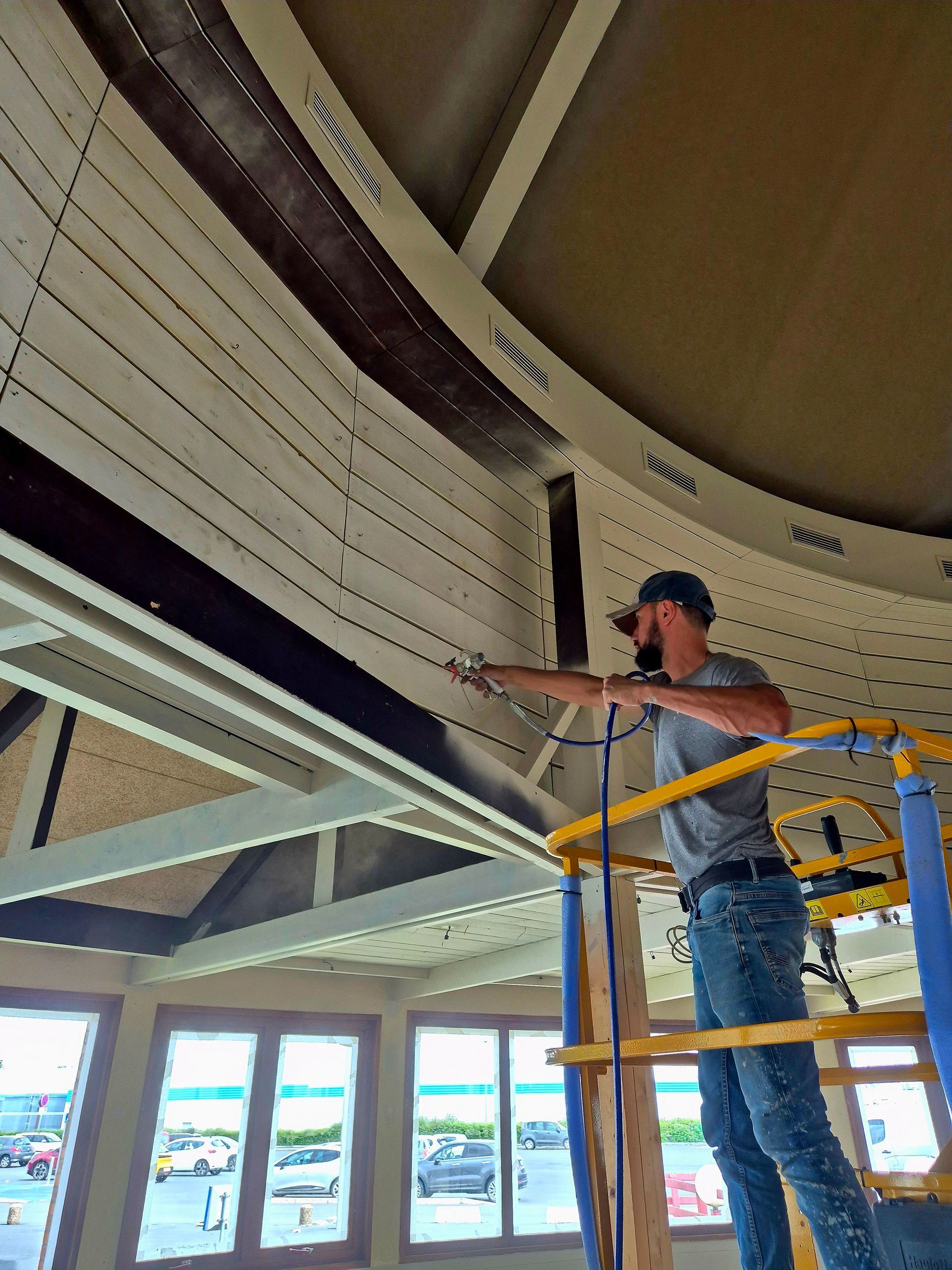 Travaux de peinture avec projection de peinture blanche sur des panneaux métalliques