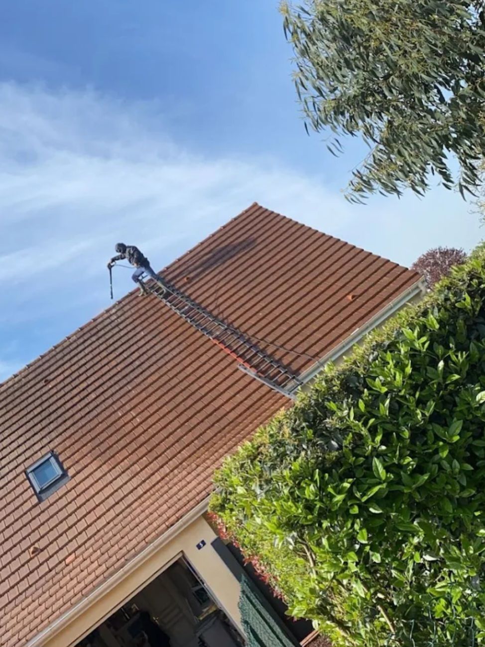 Nettoyage en cours d'une toiture avec des ardoises cuivrées