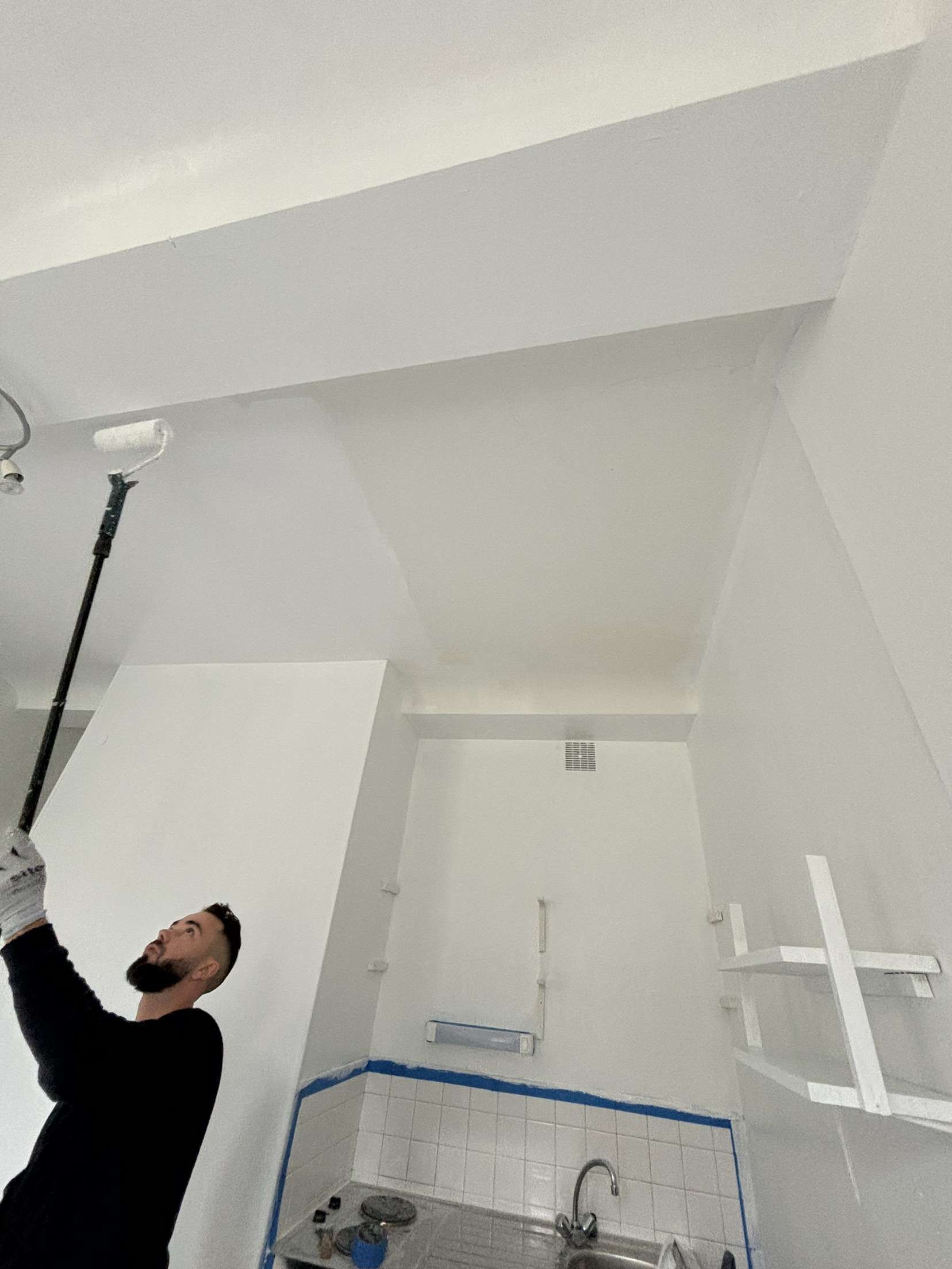 Peintre en bâtiment qui peint un plafond à l'aide d'un rouleau