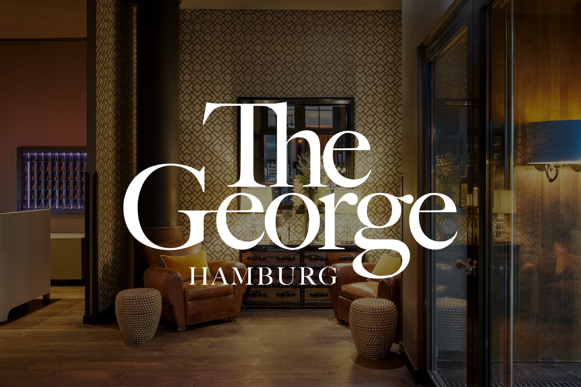 Luxuriöse Hotellobby im The George Hamburg mit warmer Beleuchtung und gemusterter Tapete.