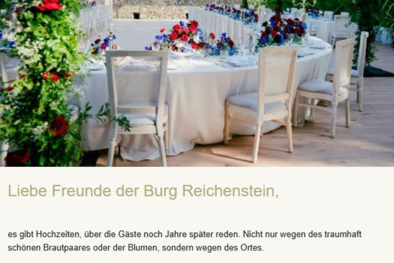 Weißer Hochzeitstisch im Freien mit Blumengestecken und weißen Stühlen an einer Steinmauer, deutscher Text darunter