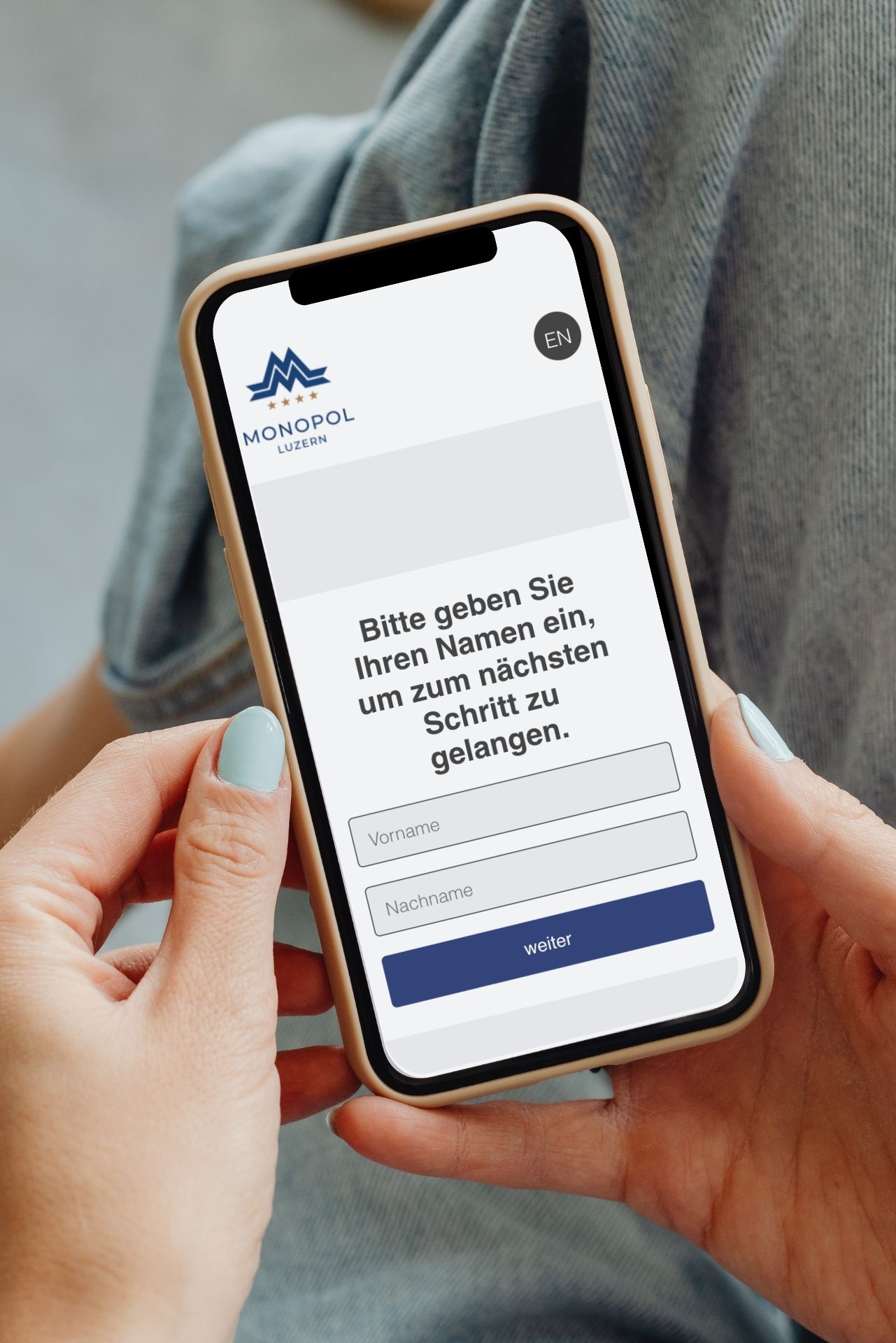 Hände halten ein Smartphone, auf dem ein hebräischer Anmeldebildschirm mit einem blauen Knopf zu sehen ist.