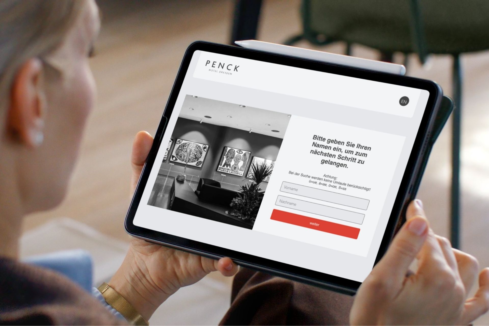 Person hält ein Tablet in der Hand, auf dem eine Webseite mit Graustufenfotos und roten Schaltflächen angezeigt wird.