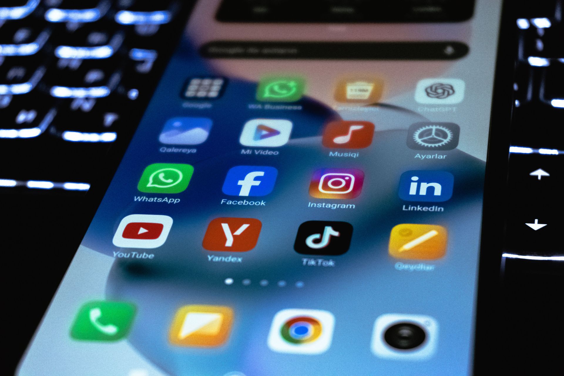 Smartphone-Startbildschirm mit farbenfrohen App-Symbolen auf einem Laptop-Tastaturhintergrund