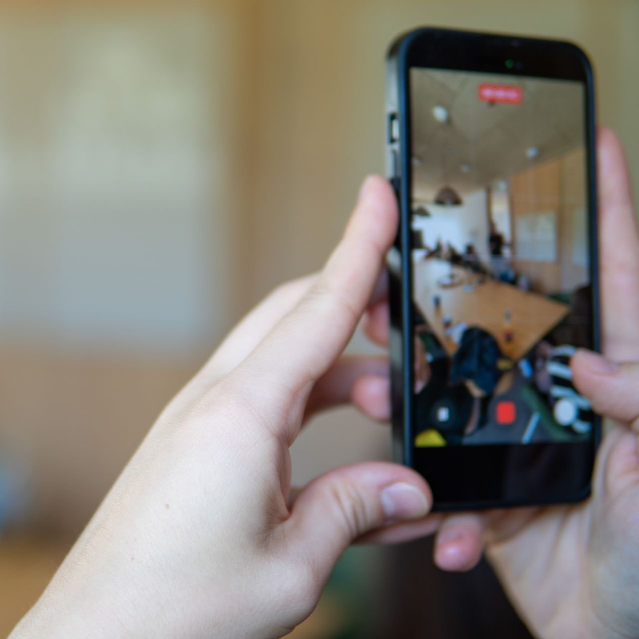 Hände halten ein Smartphone und filmen einen Raum mit einer Videokamera-App.