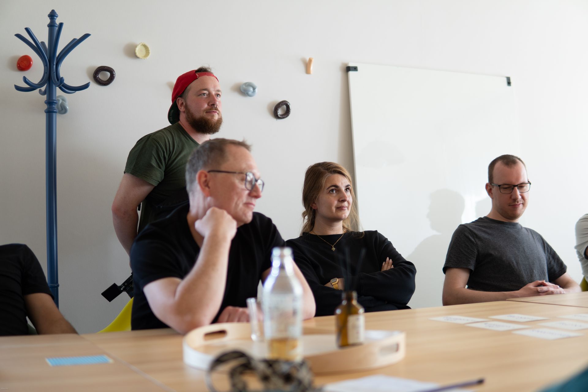 Vier Personen sitzen an einem Konferenztisch in einem hellen Besprechungsraum und hören aufmerksam zu.