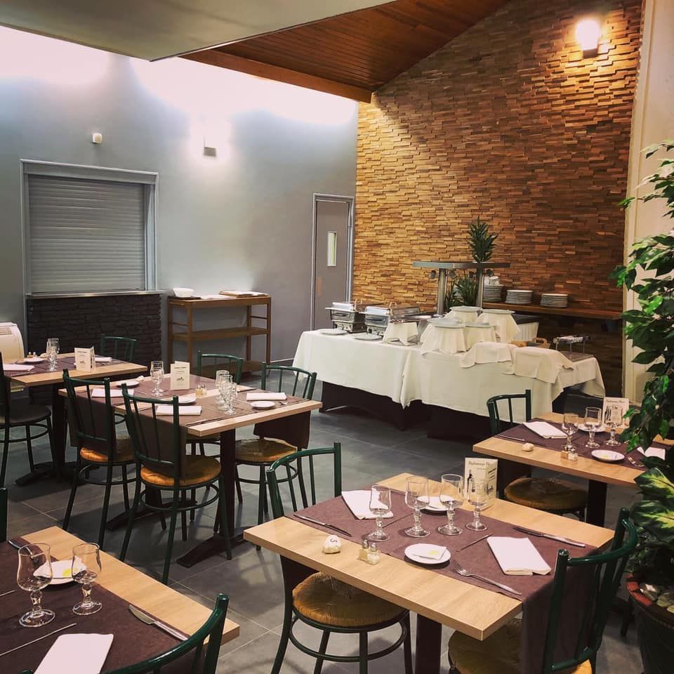 Salle à manger du restaurant avec tables dressées pour le service, buffet en arrière-plan, mur en briques.