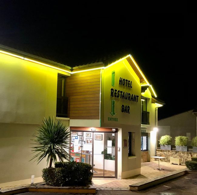 Entrée de l'hôtel la nuit, éclairée de lumières jaunes.