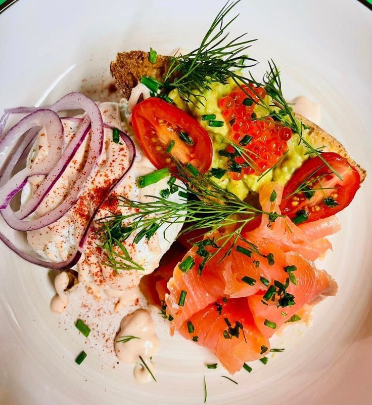 Assiette : saumon fumé, toast à l'avocat, œuf poché, tomates, oignon rouge, aneth et ciboulette.