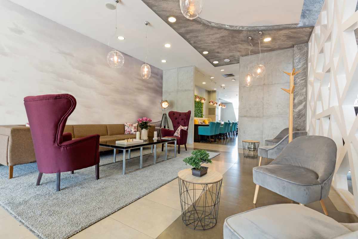 Cozy waiting area with red and gray armchairs, a long brown sofa, and a decorative cloud mural.
