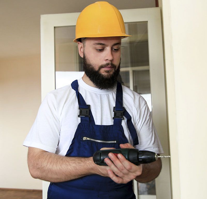 Trabajador con casco inspeccionando un taladro eléctrico en el interior.