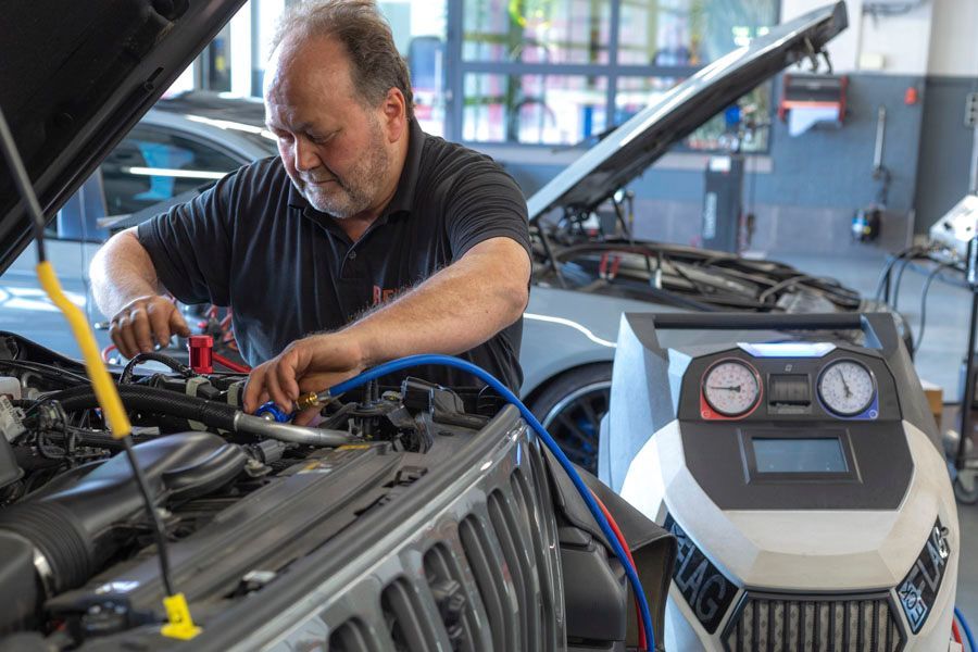 Ein Mann arbeitet in einer Garage am Motor eines Autos.
