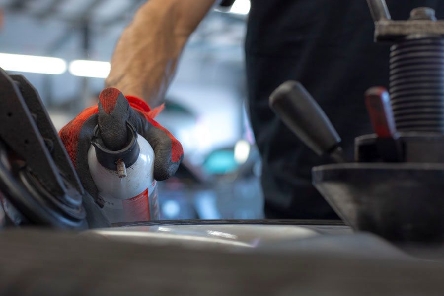 Eine Nahaufnahme einer Person, die in einer Garage eine Sprühflasche hält.