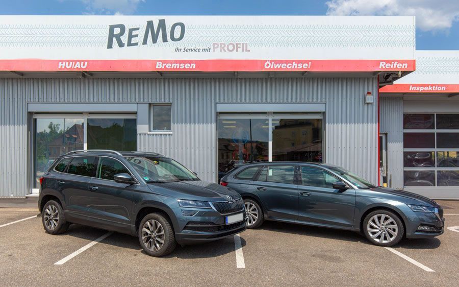 Vor einem Autohaus parken zwei Autos.