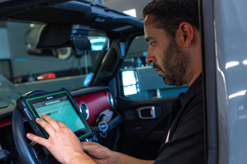 Ein Mann sitzt in einem Auto und benutzt einen Tablet-Computer.