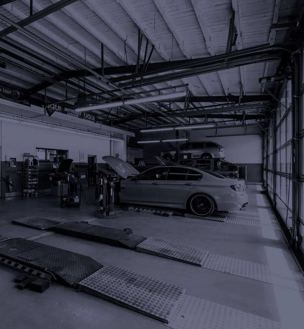 Ein Auto steht mit geöffneter Motorhaube in einer Garage.