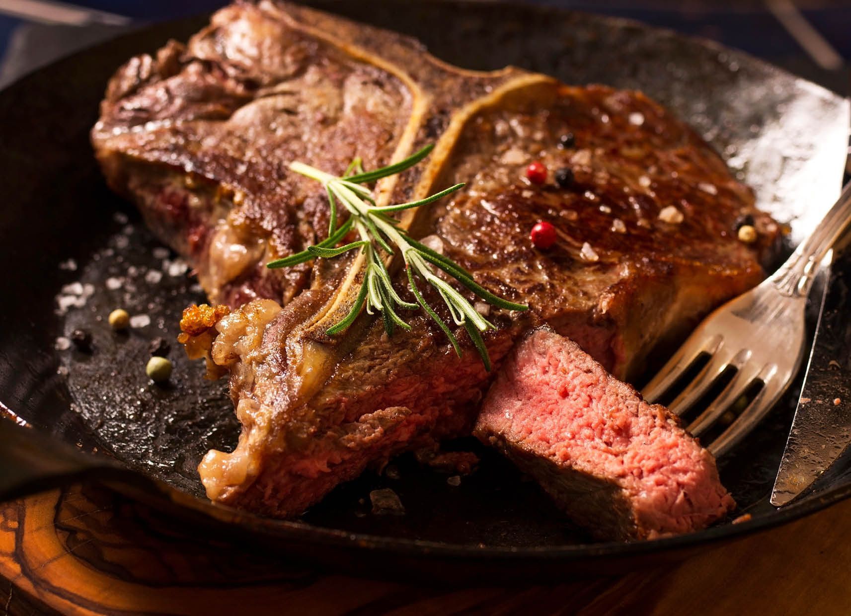 A steak is being cooked in a skillet with a fork.