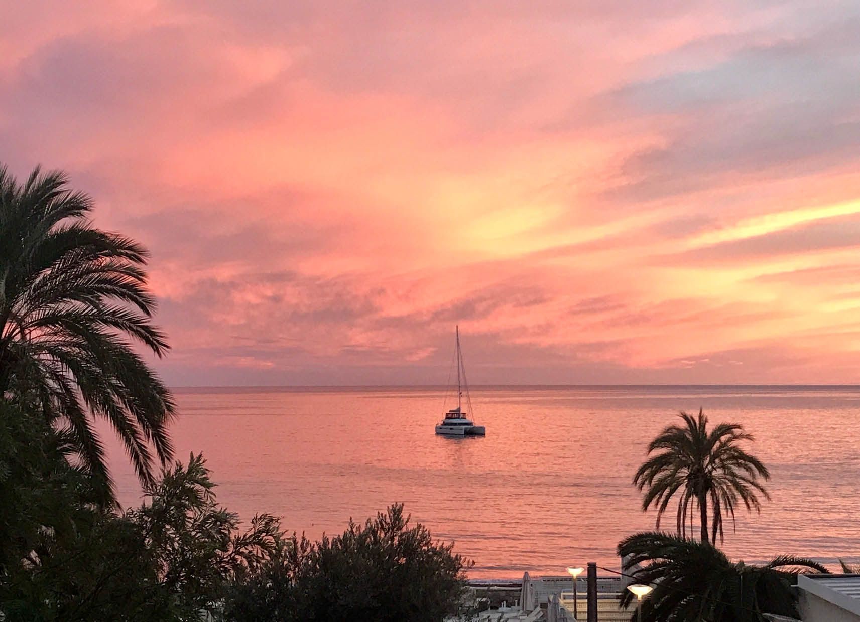 A sunset over the ocean with a boat in the water