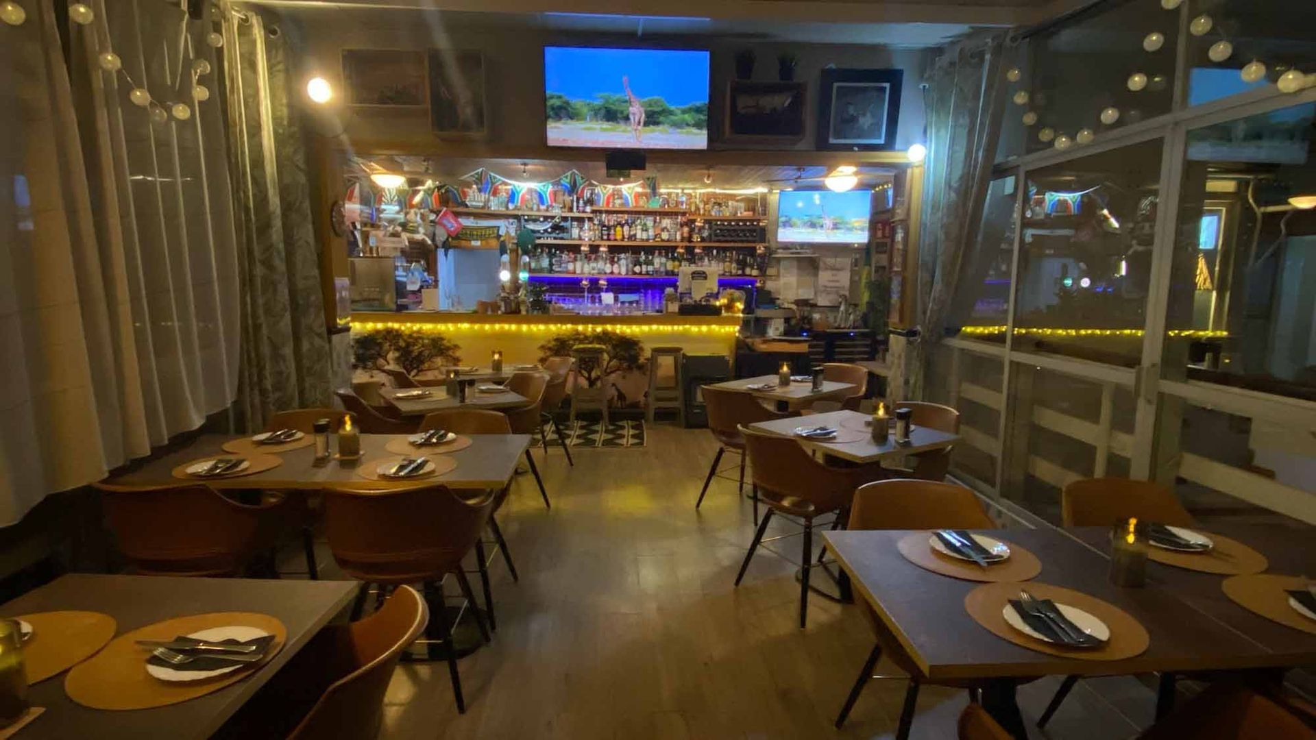 A restaurant with tables and chairs and a television on the wall.